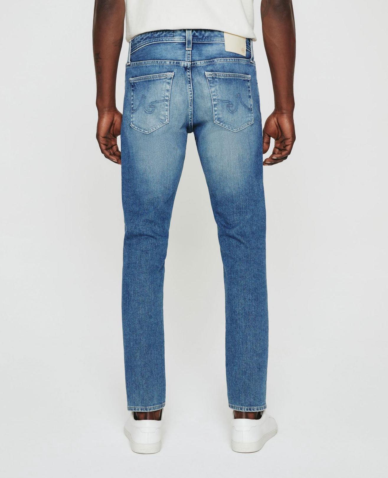 model facing sideways wearing ag jeans dylan slim fit jean in talavera blue, shown from the rear