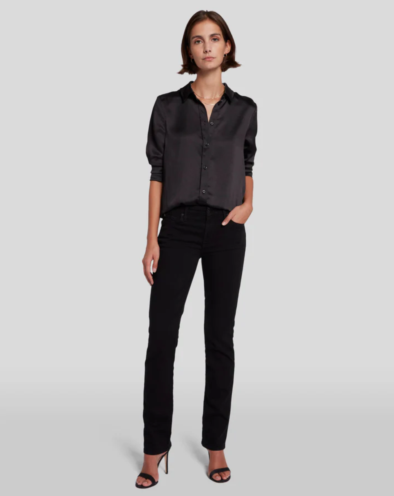 model facing forward wearing the 7 for all mankind kimmie mid rise straight in rinse black, paired with strappy sandals and black satiny blouse