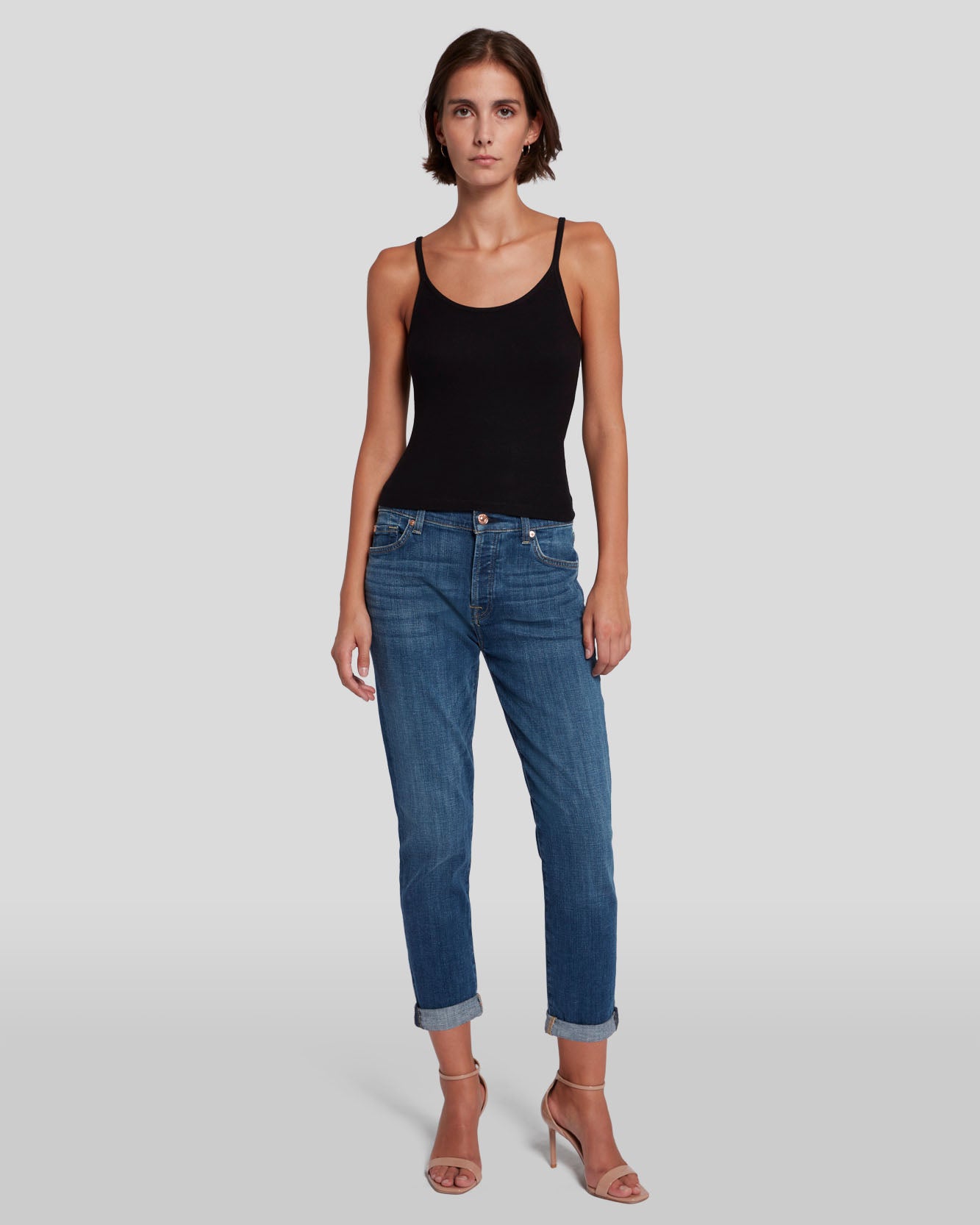 model wearing 7 for all mankind josefina boyfriend fit jean in broken twill vanity blue, paired with a black tank top and sandals
