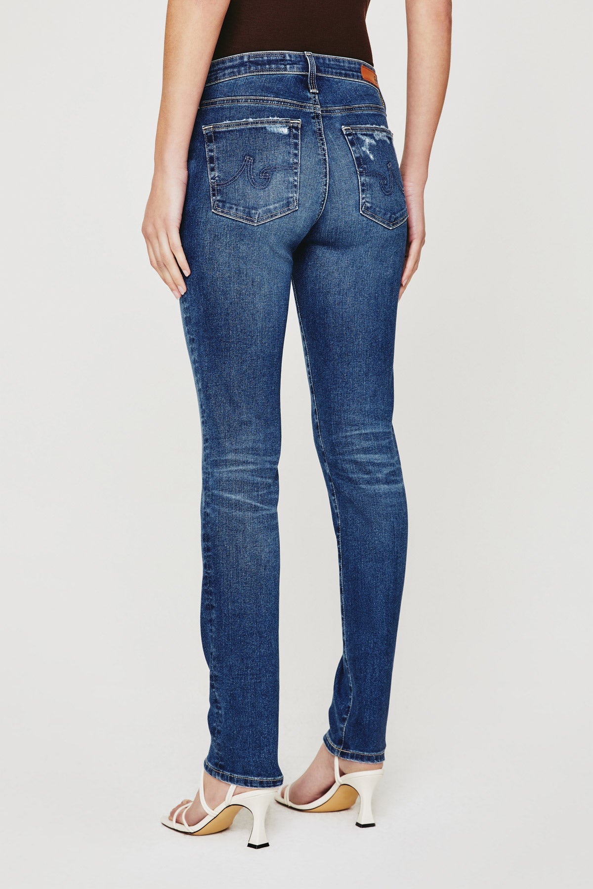 model wearing ag jeans prima mid rise slim jean in brighton blue, shown from the rear