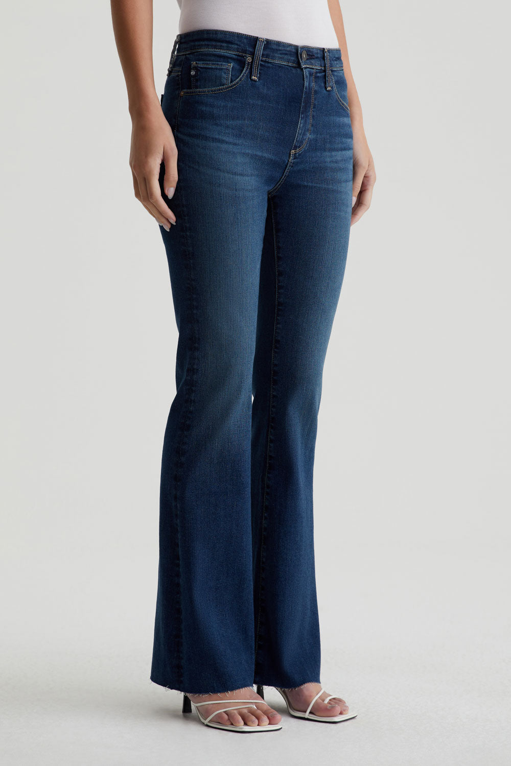 model standing at an angle wearing ag jeans farrah boot cut in kindling blue, shown from the waist down