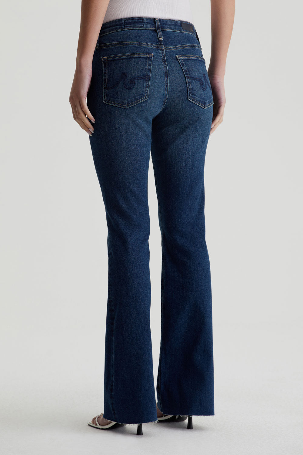 model facing away wearing ag jeans farrah boot cut in kindling blue, shown from the rear
