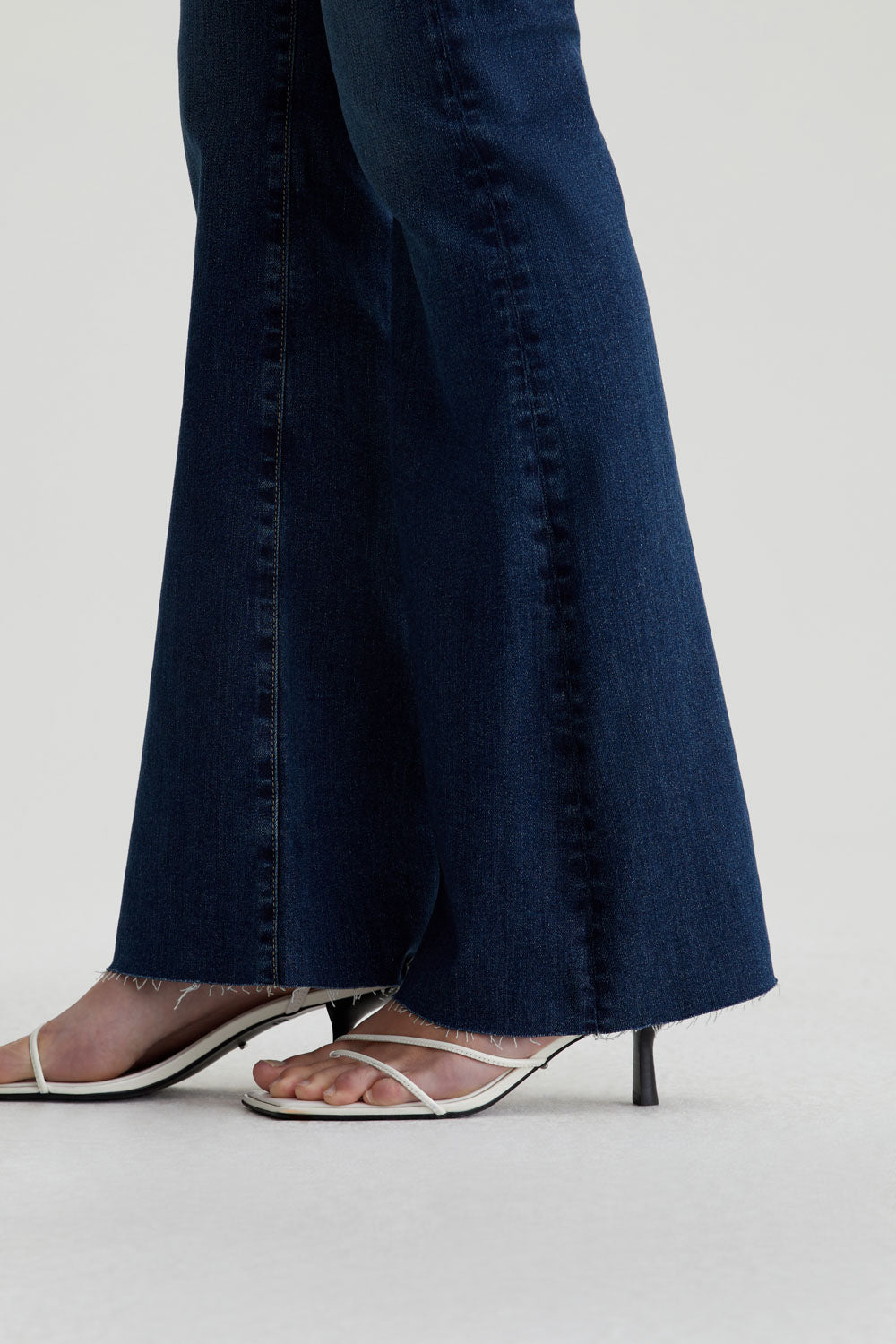 close up of the hem of ag jeans farrah boot cut in kindling blue, showing raw hem