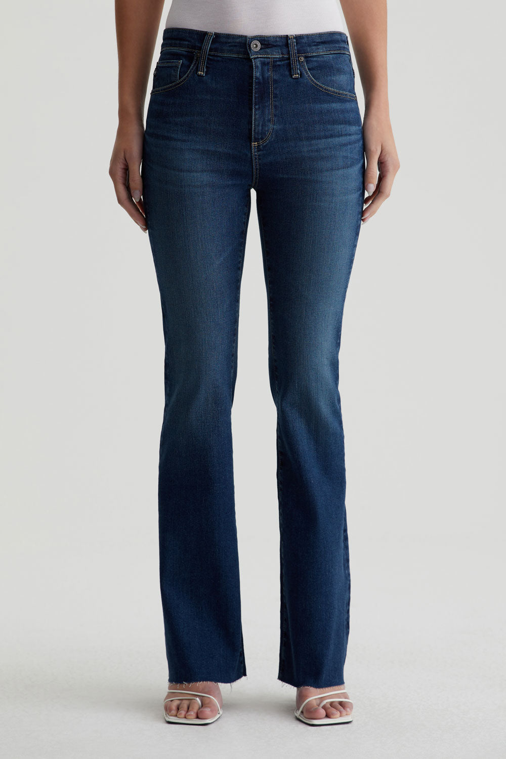 model facing forward wearing ag jeans farrah boot cut in kindling blue, shown from the waist down