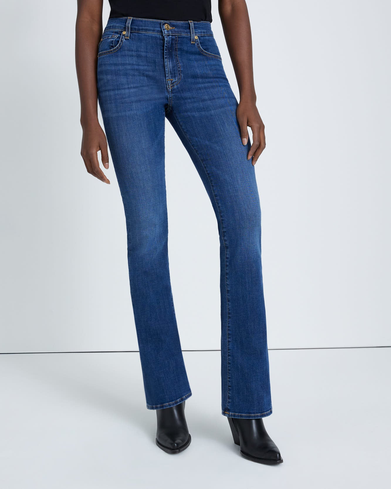 model wearing 7 for all mankind kimmie mid rise boot cut jean in duchess blue wash, shown from the waist down