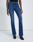 model wearing 7 for all mankind kimmie mid rise boot cut jean in duchess blue wash, shown from the waist down