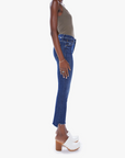 side view of the insider crop step fray jean from Mother in teaming up blue, styled with an olive green tank top and white clogs