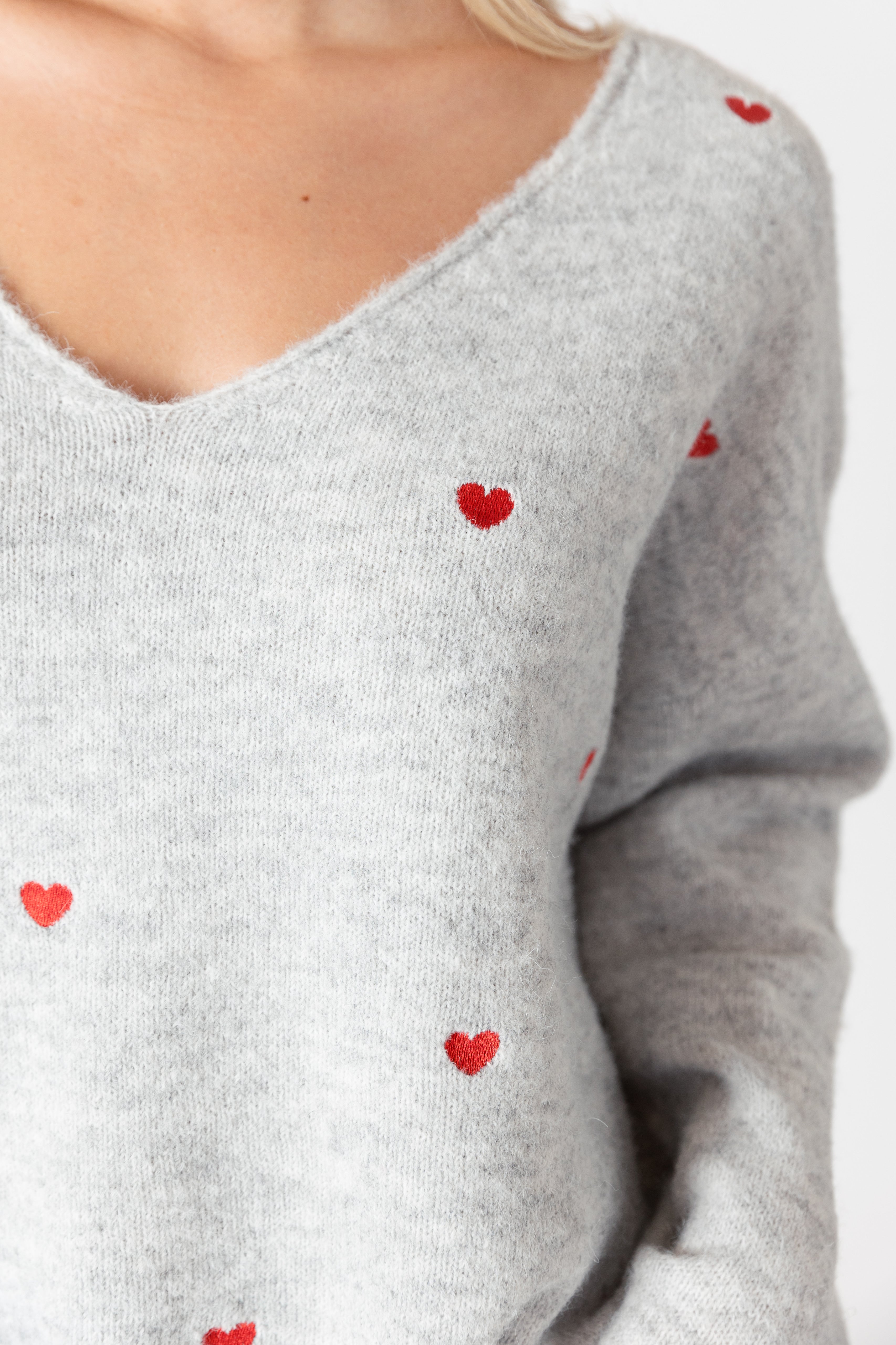 model wearing lyla &amp; luxe luna v-neck embroidered hearts sweater, close up of embroidery