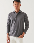 front view of the long sleeve pima stretch polo shirt in light grey, styled with white pants and model's hand in pocket