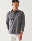 front view of the long sleeve pima stretch polo shirt in light grey, styled with white pants